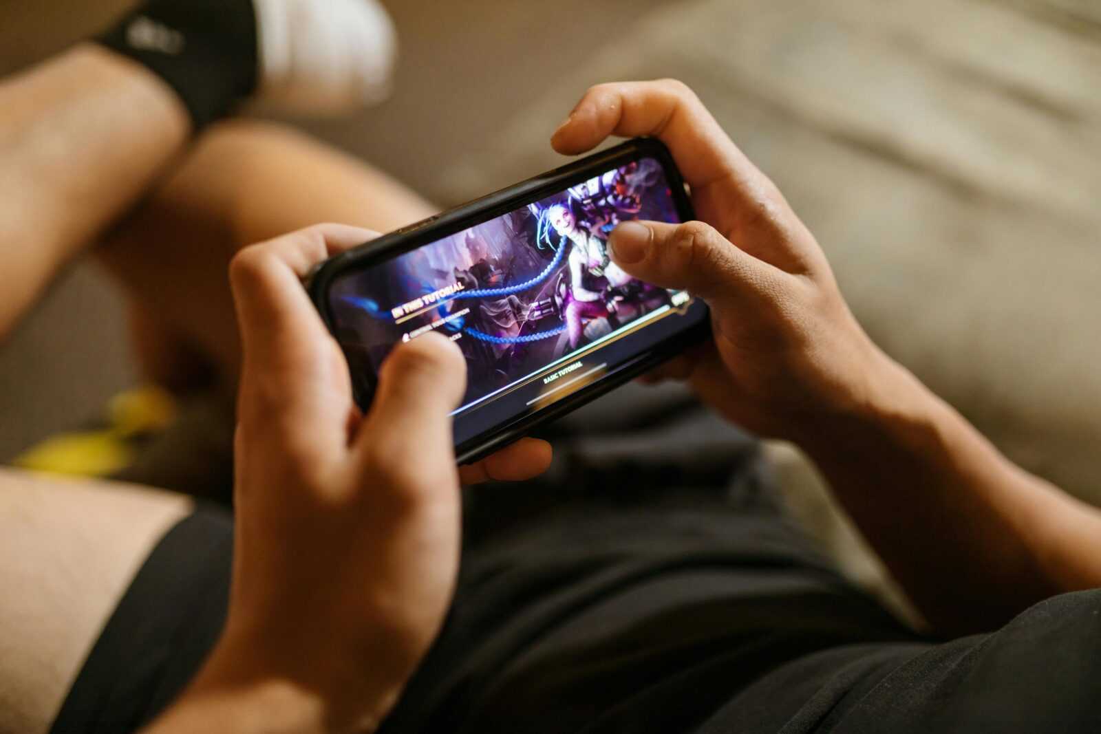 A person playing a mobile video game on a smartphone, focusing on gaming and technology lifestyle.