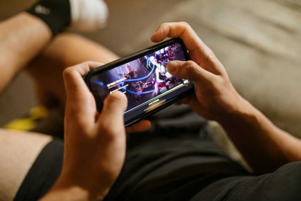A person playing a mobile video game on a smartphone, focusing on gaming and technology lifestyle.