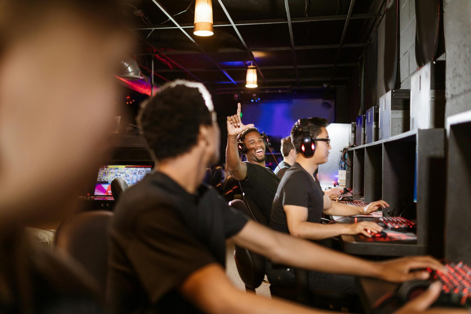 Excited gamers in an arcade setting enjoying a LAN party together, showcasing teamwork and fun.
