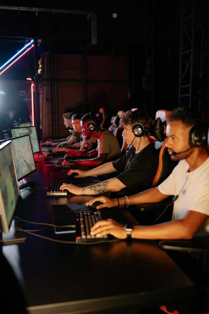 Focused gamers on computers in a dimly lit room during an intense eSports tournament.